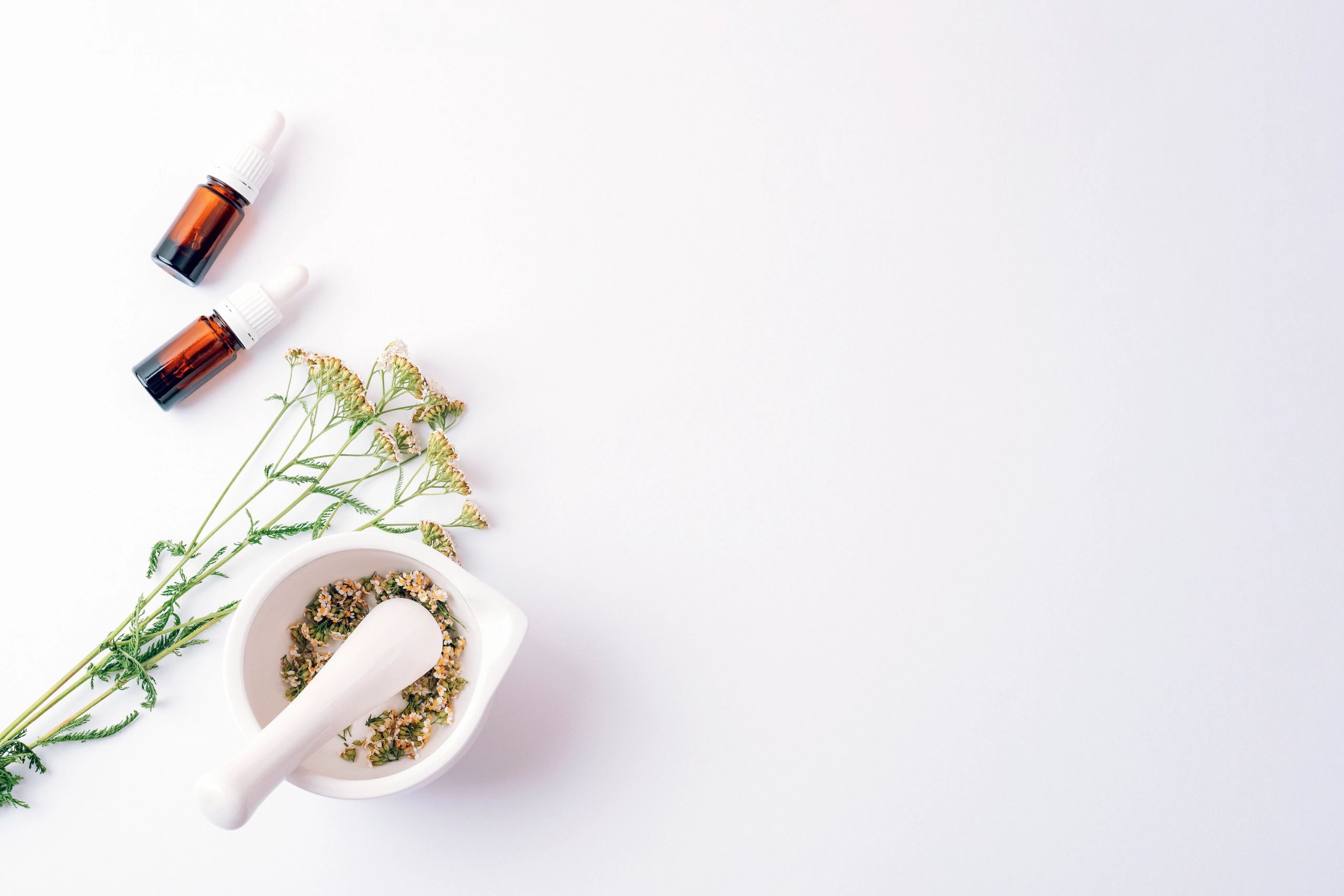 Herbal cosmetic set with essential oil bottles and dried flowers, flat lay