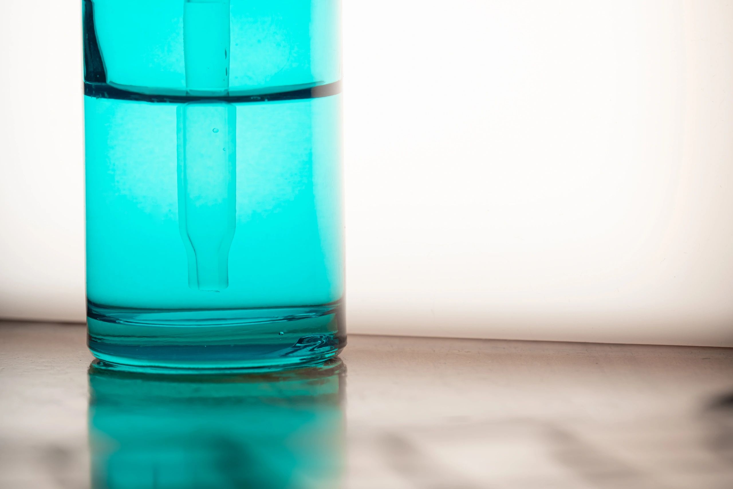 Blue glass serum dropper bottle on a clean, minimal background